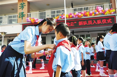     6月1日，在银川市兴庆区唐徕小学南校区，高年级少先队员为新入队的少先队员佩戴红领巾。本报记者  武晓瑜  摄